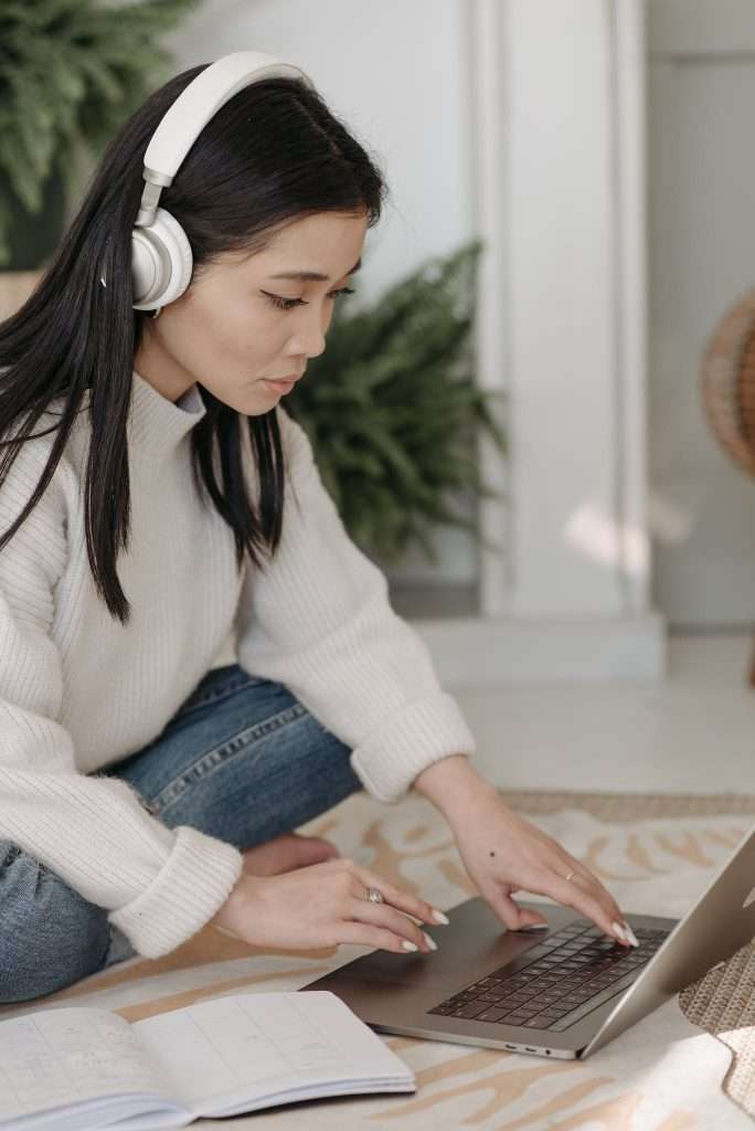 Woman with White Headphones Working on Her Laptop
